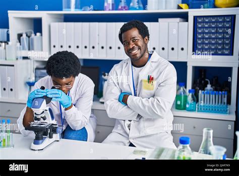 African American Man And Woman Scientists Using Microscope At