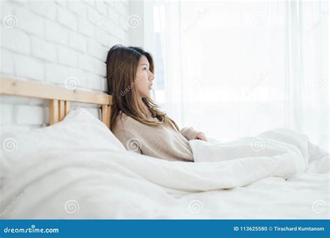 Happy Beautiful Young Asian Woman Waking Up In Morning Sitting On Bed Stretching In Cozy