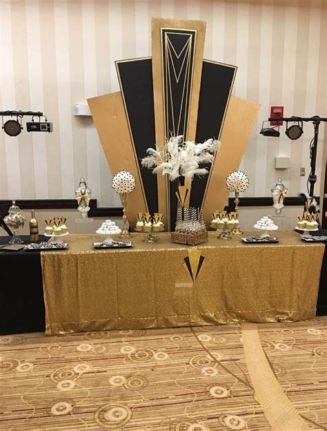 The Table Is Set Up With Gold And Black Decorations For An Event Or Party