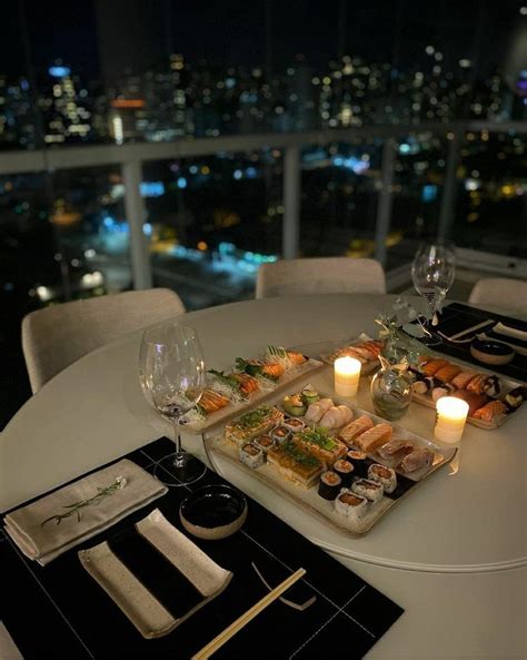 A Table Topped With Sushi And Candles Next To A Glass Of Wine In Front