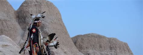 a native american man standing in front of some rocks