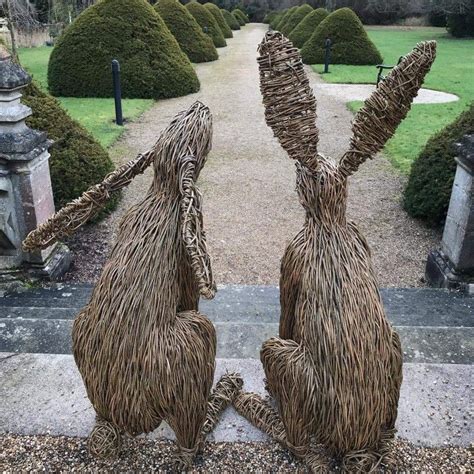 Two Statues Made Out Of Straw Sitting On Top Of A Stone Walkway