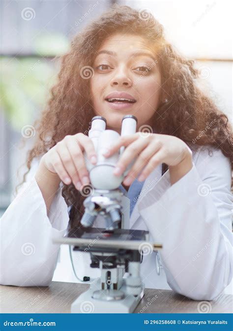 Attractive Female Scientist Looking Through A Microscope Stock Photo