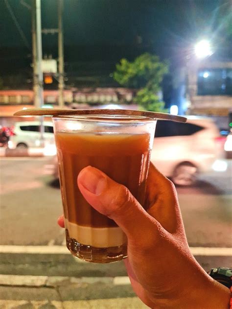 a person holding up a drink on the street