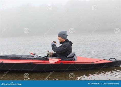 Man Sitting In Canoe Resting After Active Paddling On Kayak Drinking