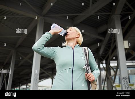 Blonde Mature Thirsty Sportswoman Drinking Water From Plastic Bottle After Hard Training In
