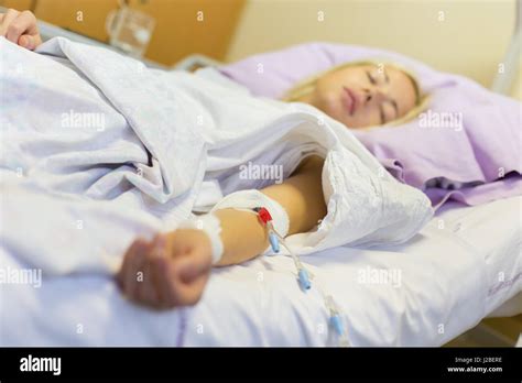 Bedridden Female Patient Lying In Hospital Bed Receive Infusion While