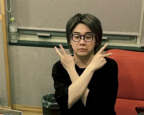 A Woman Sitting In Front Of A Red Couch Making The Peace Sign With Her