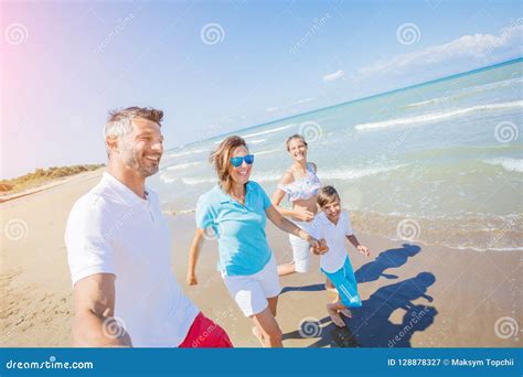 Familia De Cuatro Miembros Que Se Divierte En La Playa Imagen De