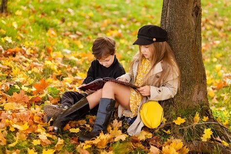 La Fille Et Le Garçon Sont Assis Sous Un Arbre Et Lisent Un Livre