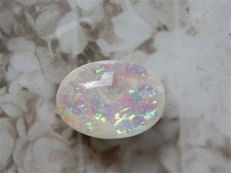 An Opalite Stone Sitting On Top Of A White Surface With Lots Of Small