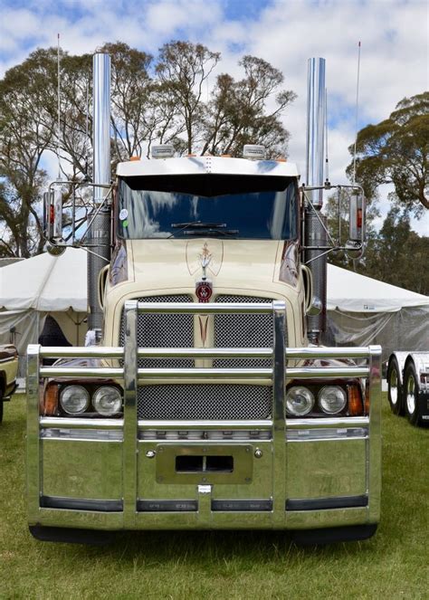 A Large Semi Truck Parked On Top Of A Lush Green Field Next To White Tents