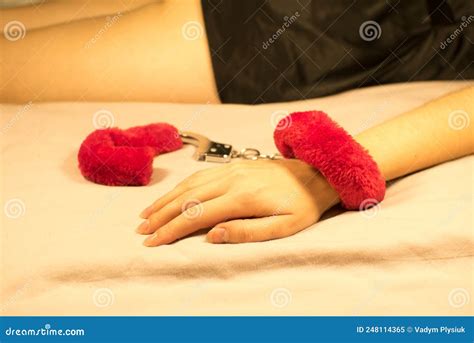 Woman Wearing Red Fluffy Handcuffs On Her Wrists In Bed Stock Image