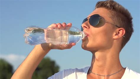 Healthy Young Man Drinking Water From The Bottle Outdoors Smiling