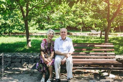 Beautiful Old Couple Is Sitting On The Bench In The Park Grandma And