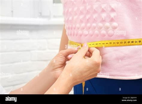 Female Doctor Measuring Waist Of Overweight Woman In Hospital Stock