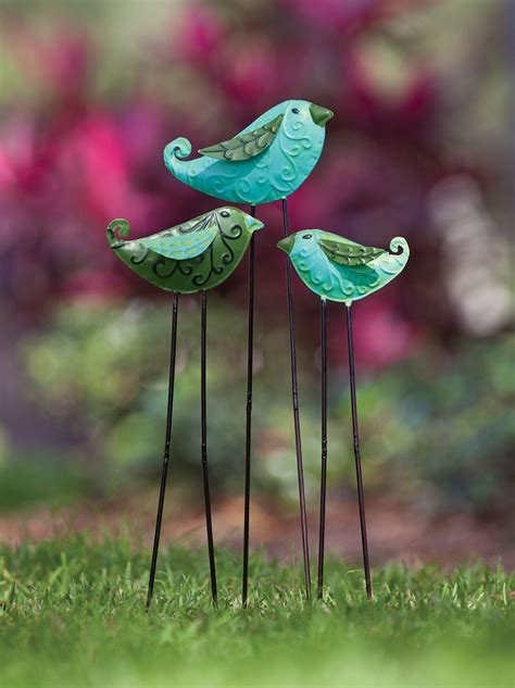 Three Metal Birds Sitting On Top Of Green Grass