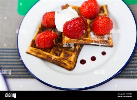 Strawberries And Whipped Cream With Mint Garnish On Waffles With