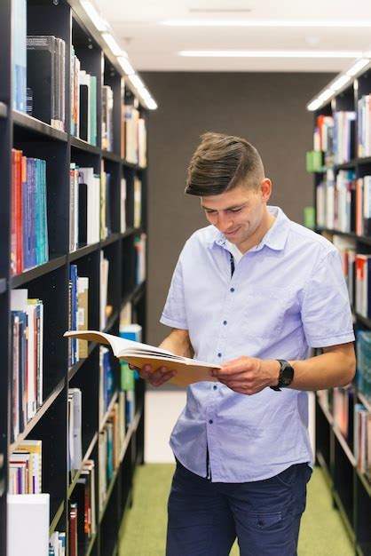 Chico Leyendo Un Libro En La Biblioteca Foto Gratis