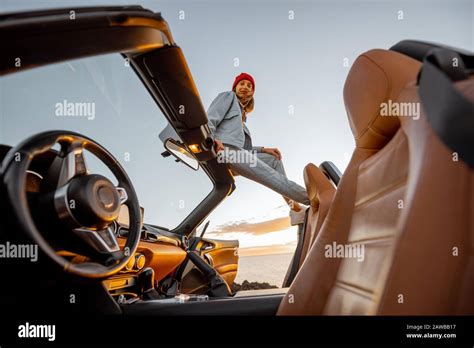 Woman Enjoying Beautiful View On The Ocean Sitting On The Car Roof Top