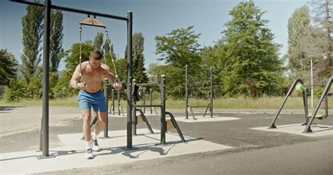 Muscular Man Getting Shredded Doing Pull Ups At An Outdoor Park Gym On