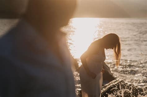 Premium Photo A Pregnant Woman Stands On A Rock In Front Of A Sunset