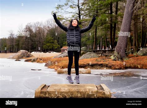 A Chinese Woman Jumping And Flashing Peace Signs On A Cememt Block At