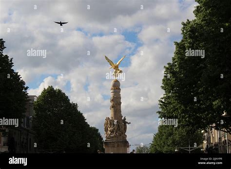 A Gold Angel Statue On Top Of A Building With A Cloudy Blue Sky In The