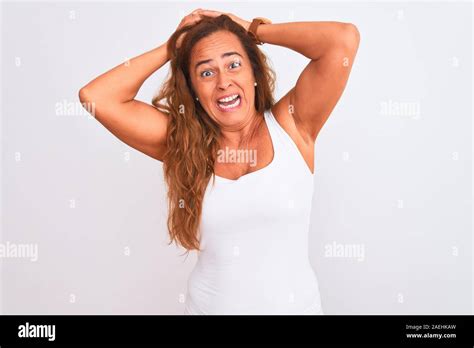 L âge moyen mature woman standing over white background isolé et fou de peur peur et surprise