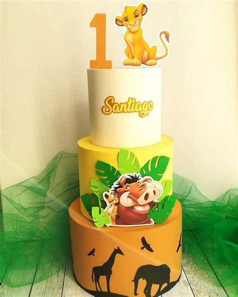 A Three Tiered Cake Decorated With Lion And Giraffes On The Top