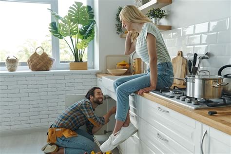 Premium Photo Cheerful Young Man Repairing A Sink While Woman Sitting