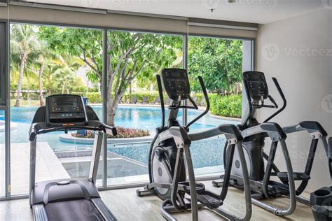 Row of treadmill machine and glass window with garden view in gym