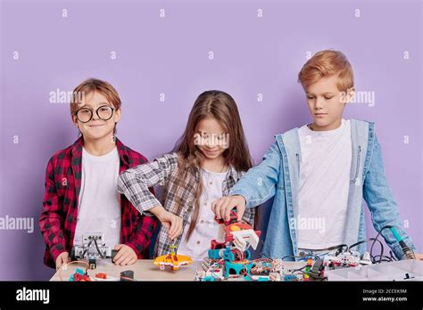 retrato de entusiastas tres niños trabajando en equipo montando robots