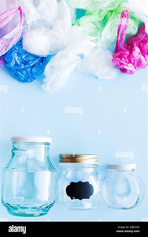 Many Disposable Plastic Bags Vs Reusable Glass Jars On A Blue