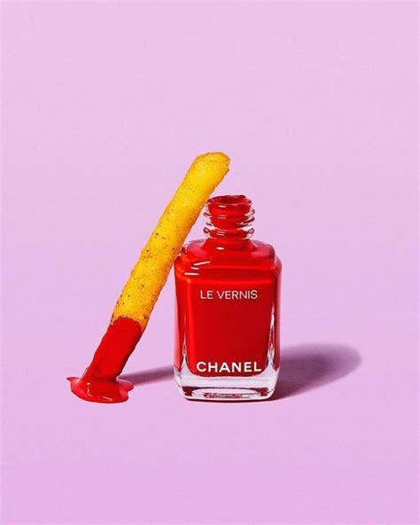 A Red Nail Polish Bottle Next To A Yellow Stick On A Pink Background