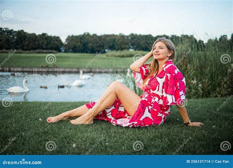 Beautiful Smiling Blonde Woman Lying On The Grass Outdoors She Is