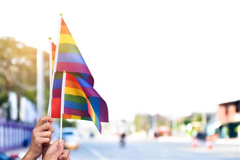 Pride Rainbow Lgbt Gay Flags Holding In Hand And Being Waved In The Breeze Against Blue Sky