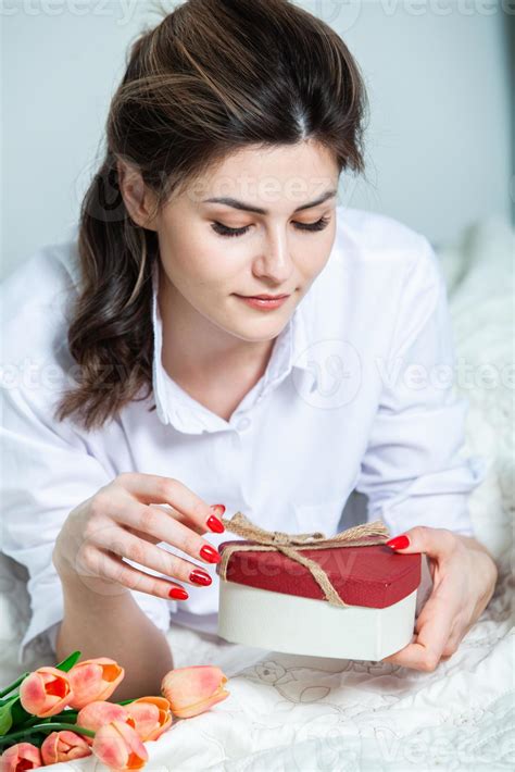 hermosa chica abre una caja de regalo de corazón rojo. día de San