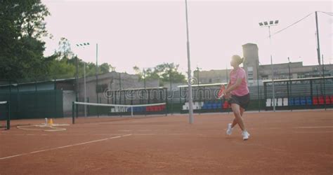 Side View Of A Young Caucasian Woman Playing Tennis On A Court