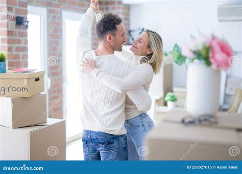 Young Beautiful Couple Dancing At New Home Around Cardboard Boxes Stock