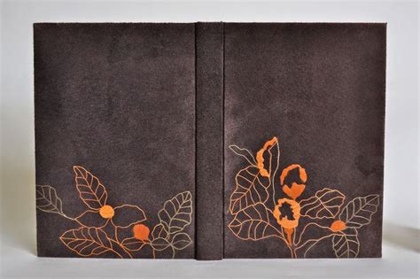 Two Brown Books With Orange Designs On Them