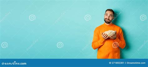 Handsome Young Man In Orange Sweater Looking Thoughtful At Upper Left