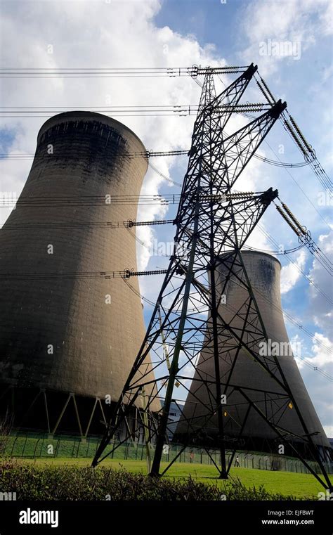 Cooling Towers And Electricity Pylons Against A Bright Cloudy Sky At