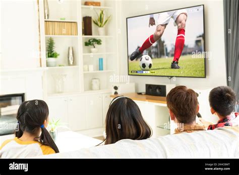 Niños diversos viendo la televisión con un partido de fútbol en la