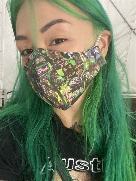 A Woman With Green Hair Wearing A Face Mask That Has Stickers All Over It