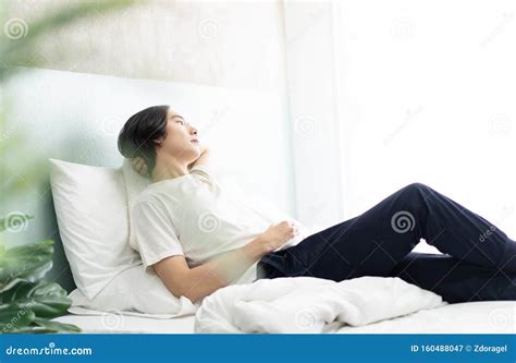 Side View Of Young Asian Man Lying In His Bed And Relaxing In The Morning People And Lifestyle