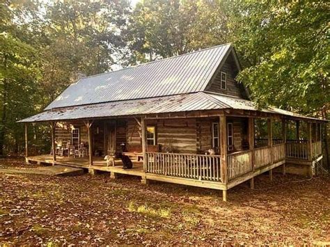 A Log Cabin In The Woods With A Porch And Covered Veranda Area