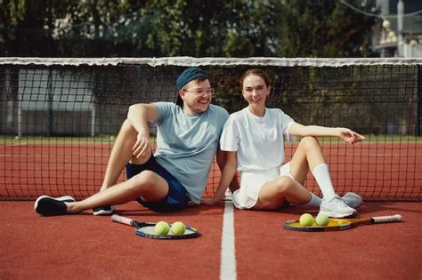 Feliz Pareja Sentada En El Suelo De La Cancha De Tenis Con Raquetas Y