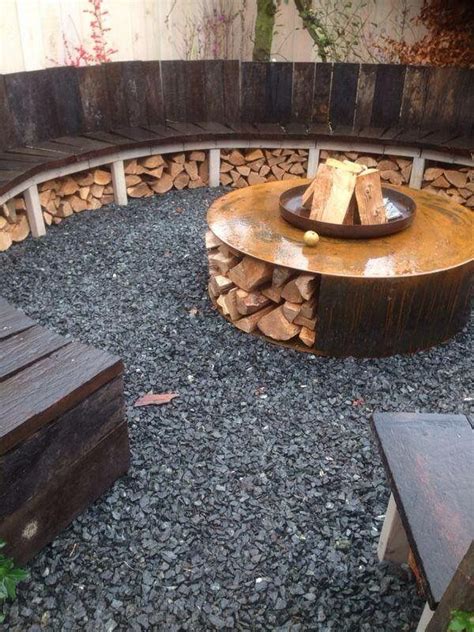 An Outdoor Fire Pit Surrounded By Logs And Wooden Benches In The Middle