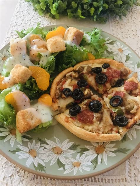 Two Pizzas With Different Toppings On A Green Plate Next To Salad And Bread